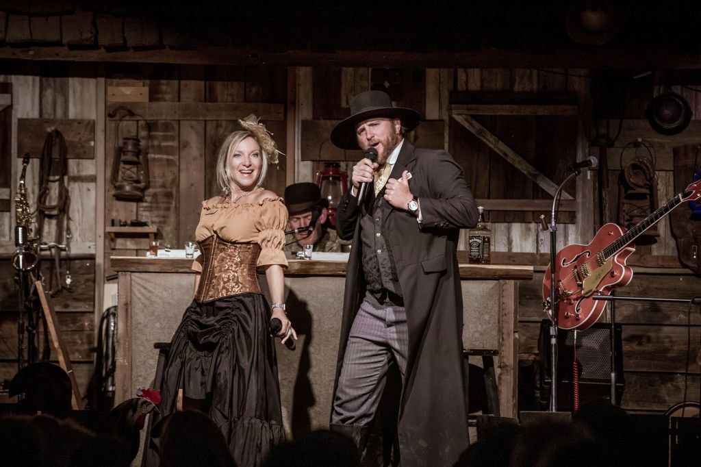 A man and woman in Western costumes perform on stage.