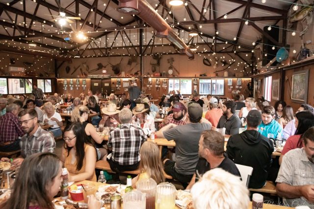 Large group of people dining together in a rustic, decorated hall.