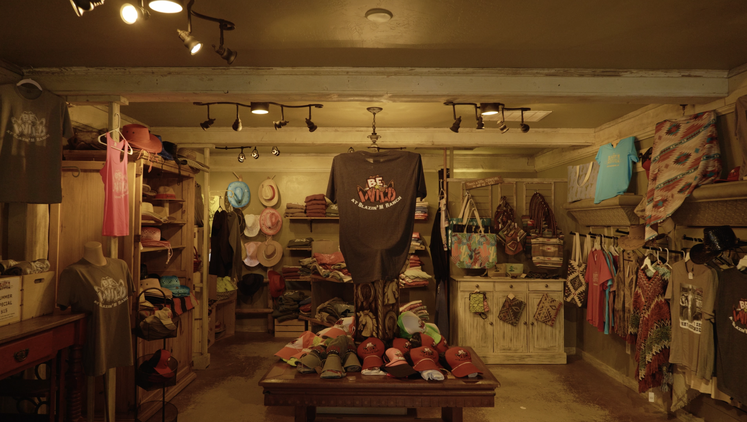 Rustic shop interior with clothes, hats, and accessories displayed on shelves and a table.