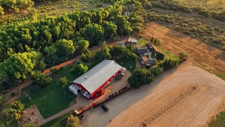 Aerial view of a rural property with a red-roofed building and surrounding fields.
