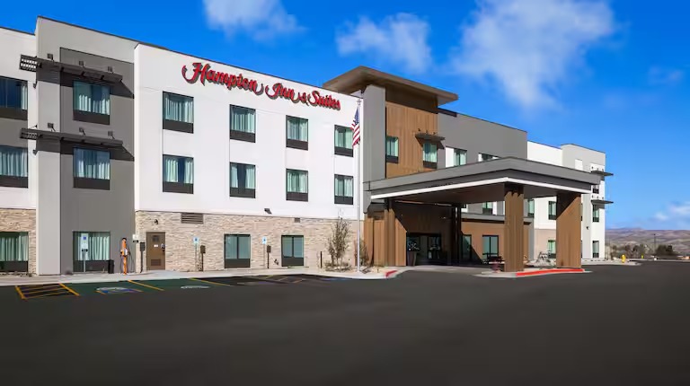 Modern hotel exterior with a covered entrance and an American flag displayed.