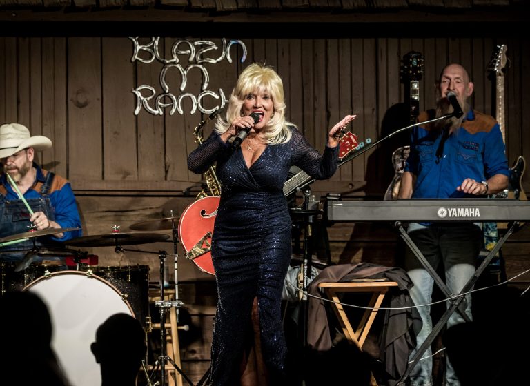 Woman singing on stage with band at Blazin M Ranch.