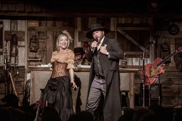 A man and woman in Western costumes perform on stage.