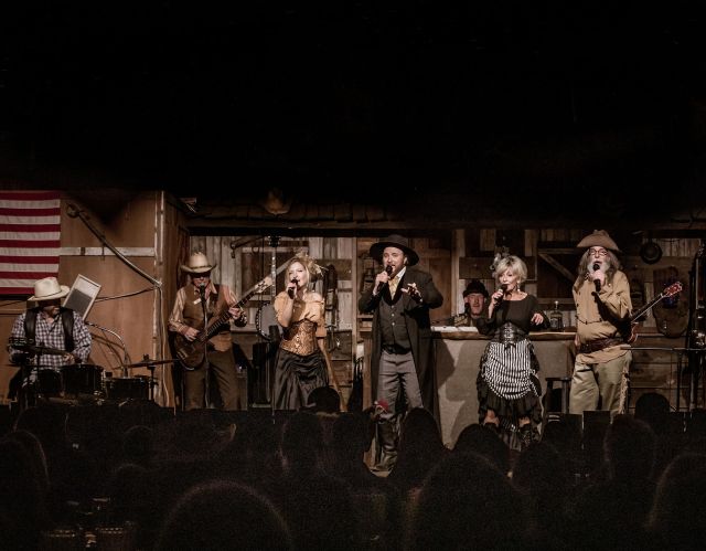 Band performing on stage with various musicians and singers.