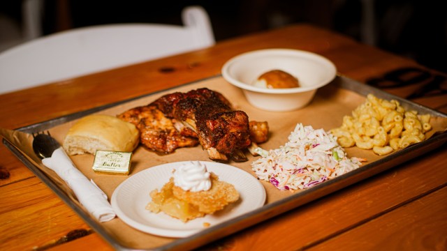 Meal with chicken, mac and cheese, slaw, roll, and dessert on a tray.