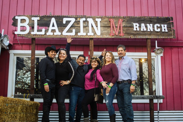 Group of six people posing in front of Blazin M Ranch sign.