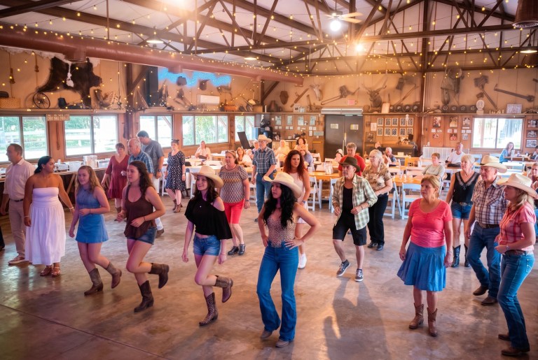 Group of people line dancing in a decorated indoor venue.
